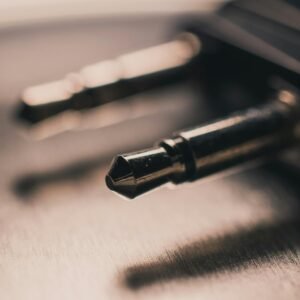 Macro close-up of a metallic audio jack placed on a brushed metal surface, emphasizing texture.