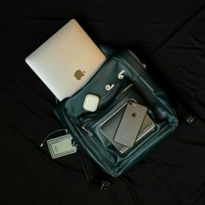 Top view of a backpack with a laptop, smartphone, and earphones, showcasing modern technology essentials.