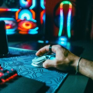 Hand operating a gaming mouse with vibrant neon lights in an atmospheric tech setting.