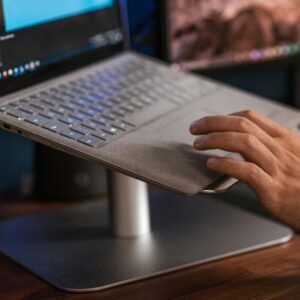 Crop unrecognizable male browsing modern netbook and scrolling touchpad placed on stand on desk