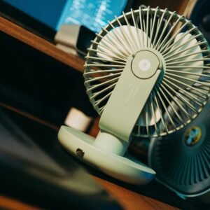 Photo of a desk setup featuring a modern compact fan, emphasizing technology and comfort.