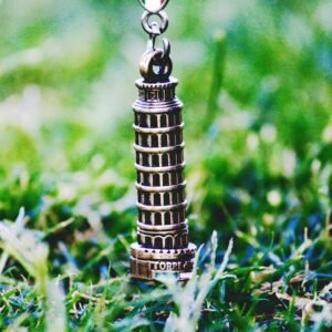 Keychain of Leaning Tower of Pisa in a grassy field. Perfect for travel and souvenir themes.